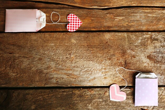 Etiquetas de bolsitas de té en forma de corazón sobre fondo de madera