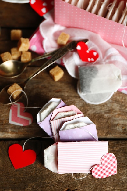 Etiquetas de saquinho de chá em forma de coração e caixa em fundo de madeira