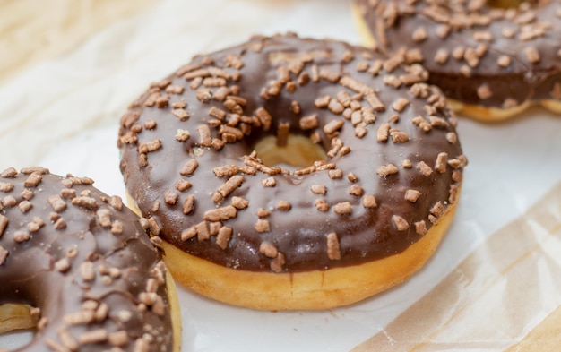 etwas schokoglasierter donut auf backpapierköstliches leckeres dessert mit schokoladenpartikeln über