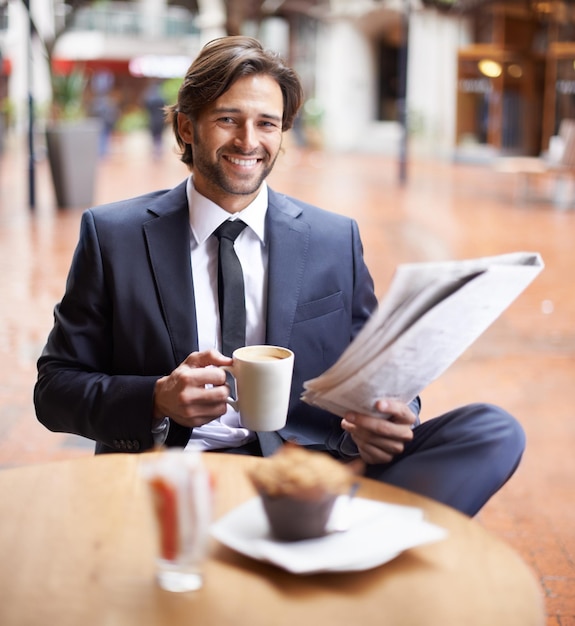 Etwas Zeit für mich selbst inmitten eines anstrengenden Tages Ein Geschäftsmann, der eine Kaffeepause macht, während er die Nachrichten liest