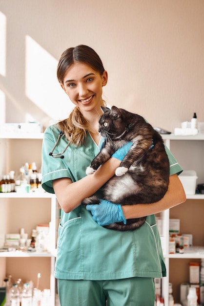 Foto eu amo cada uma das minhas pacientes, veterinária sorridente segurando uma grande gata preta fofa