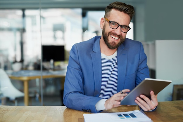 Eu crio todos os meus conceitos vencedores neste dispositivo prático Retrato de um jovem empresário trabalhando em um tablet digital em um escritório