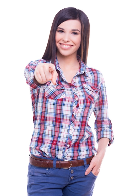 Eu fiz minha escolha! Mulher jovem e atraente sorridente olhando para a câmera e apontando para você enquanto fica isolado no branco