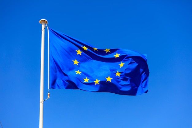 EU-Flagge Flagge der Europäischen Union auf einer Stange weht auf blauem Himmelshintergrund