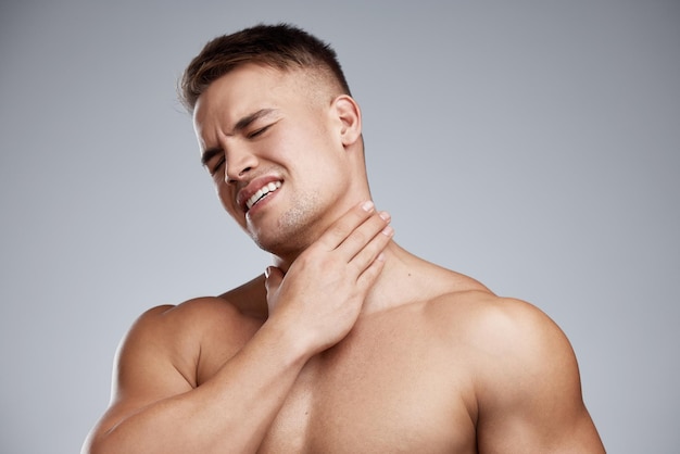 Eu fui longe demais desta vez foto de estúdio de um jovem musculoso com dor no pescoço contra um fundo cinza