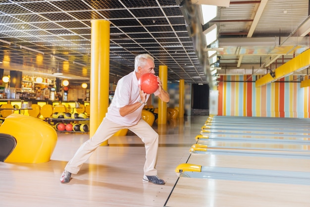 Eu quero greve. Homem bom e ativo segurando uma bola enquanto mira nos boliches