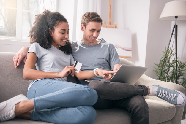 Eu quero isso. Mulher simpática e feliz apontando para a tela do laptop enquanto mostra o que quer comprar