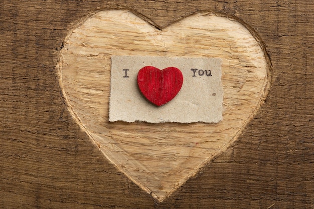 Eu te amo pequena nota de texto digitada fechar o conceito de cumprimentos do Dia dos Namorados Forma de coração esculpida em madeira como plano de fundo para cartão de saudação dos namorados