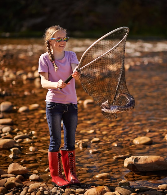 Eu tenho uma foto de uma jovem segurando uma rede de pesca com um peixe nela