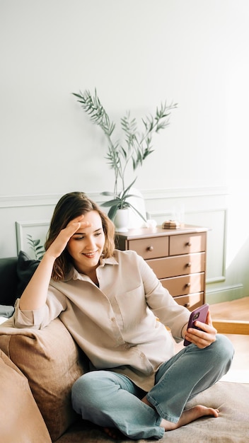 Eufórica Tech Delight Mujer millennial alegre se ríe mientras está absorta en su teléfono leyendo mensajes