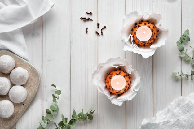 Eukalyptuszweigkerzen in Pomanderball Orangen Schere und Lebkuchen auf Schneidebrett