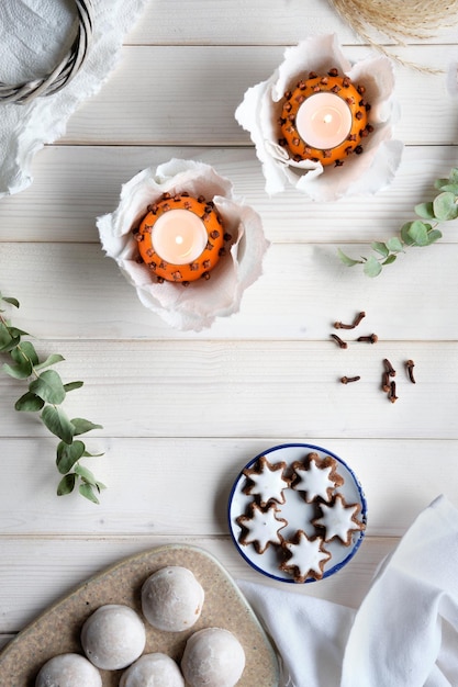 Eukalyptuszweigkerzen in Pomanderball Orangen Schere und Lebkuchen auf Schneidebrett