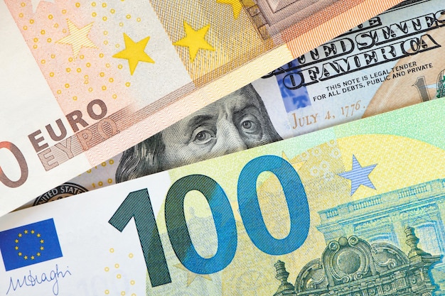 Euro- und Dollarnoten Euro gegen Dollar Ein genauerer Blick auf den Präsidenten der USA mit einem Dollarschein, der hinter einem Euroschein hervorschaut Finanzbeziehung zwischen den USA und Europa Nahaufnahme von oben