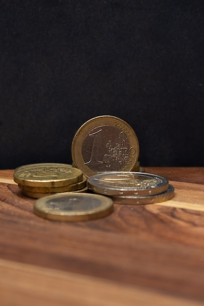 Un euro y varias monedas en el fondo de madera.