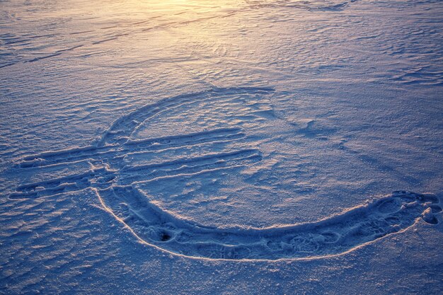 Euro-Währungssymbol auf den Schnee gezeichnet. Sonnenuntergang im Hintergrund.