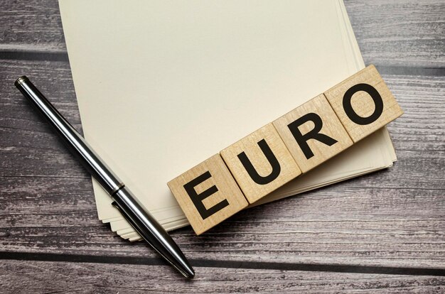 Foto euro word in hölzernen würfeln auf einem notizbuch mit stift geschrieben