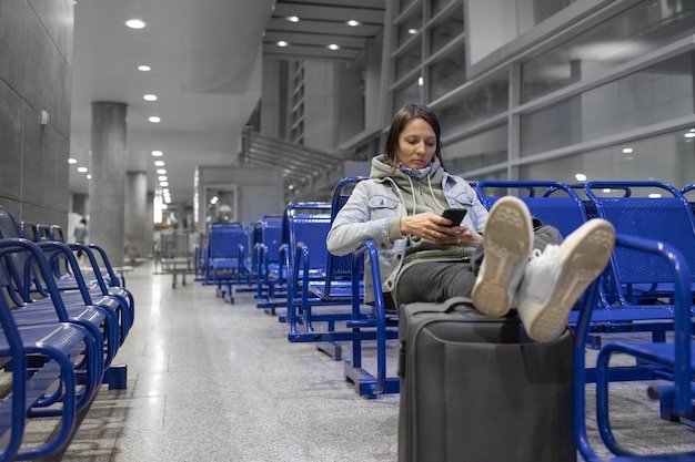 Europäische Frau am Flughafen, die darauf wartet, ihren Flug zu besteigen, und Verspätungen beim Boarding