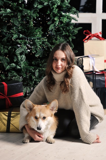 Europäische kaukasische junge Frau sitzt unter einem Weihnachtsbaum