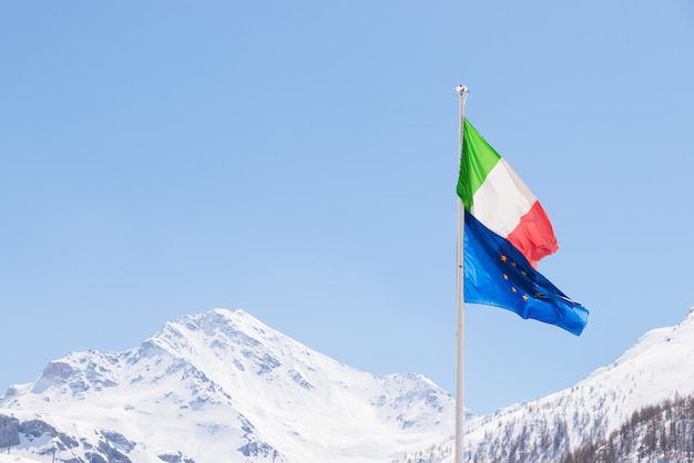 Europäische Union und italienische Flagge weht im Wind auf den Alpen