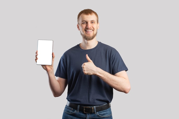 Europäischer Mann mit einem Tablet in der Hand auf einem isolierten grauen Hintergrund