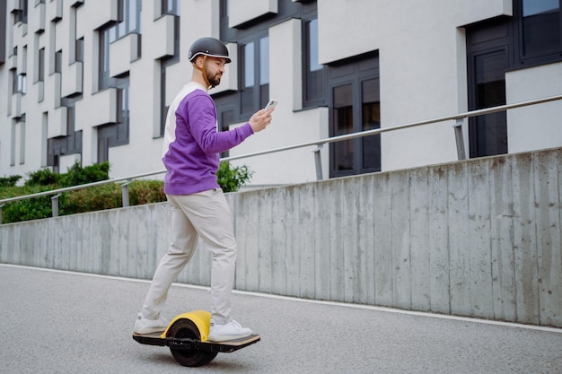 Europäischer Mann mit Elektro-Skateboard junger gutaussehender Mann, der das Foto in hoher Qualität verwendet