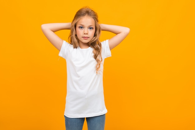 Europäisches attraktives Mädchen in einem weißen T-Shirt mit einem Modell auf einem gelben