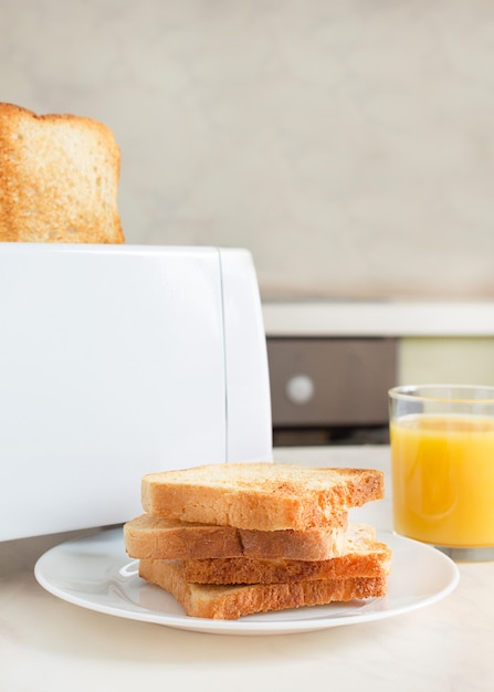 Europäisches Frühstück in der Küche am Morgen. Weißbrot Toaster mit Orangensaft mit Toast.