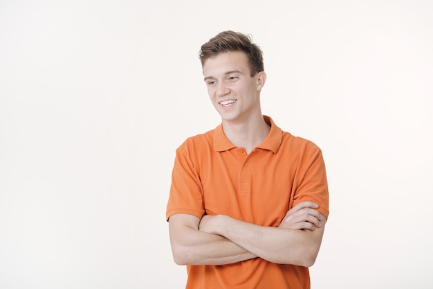 Europeu com aparência amigável e camisa laranja sorrindo em pé