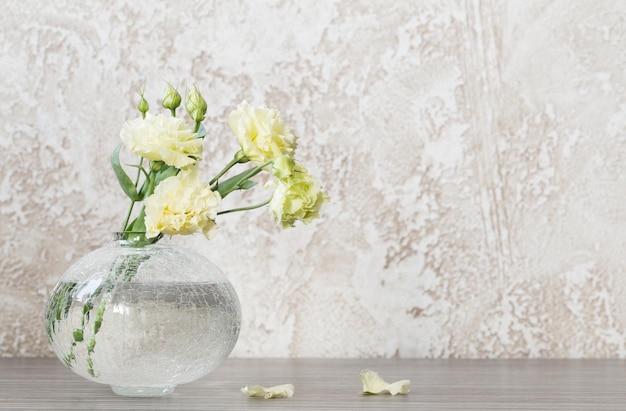 Eustoma amarillo en jarrón de vidrio sobre mesa