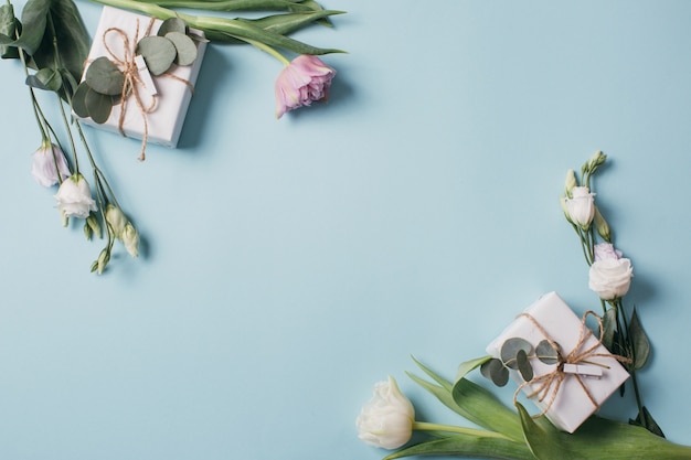 Eustoma, Eukalyptus, Tulpen und Geschenkboxen auf einem blauen Hintergrund