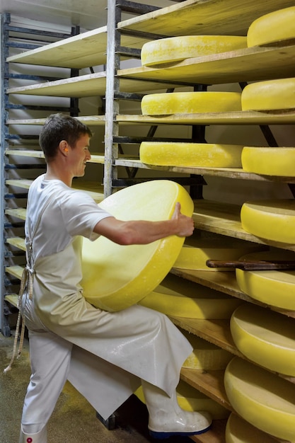 Evillers, Frankreich - 31. August 2016: Arbeiter entfernen alternden Gruyere de Comte-Käse aus dem Holzregal im Reifekeller der Molkerei Franche Comte in Frankreich