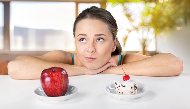 Evite el concepto de alimentos azucarados, mujer eligiendo entre pastel y manzana