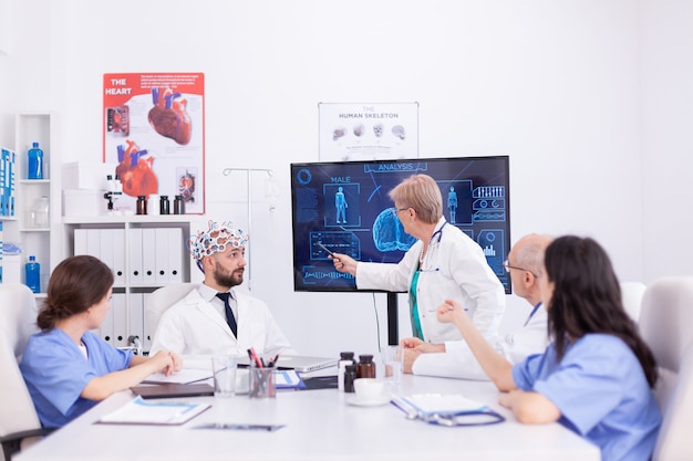 Exame de eletroencefalograma de ondas cerebrais em hospital por médico. o monitor mostra um estudo moderno do cérebro enquanto a equipe de cientistas ajusta o dispositivo.