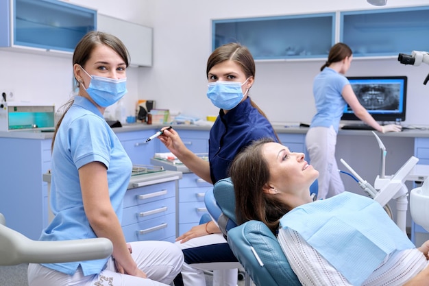 Examen dental, tratamiento de dientes, paciente mujer madura en silla y médico dentista con asistente. Concepto de medicina, odontología y salud.