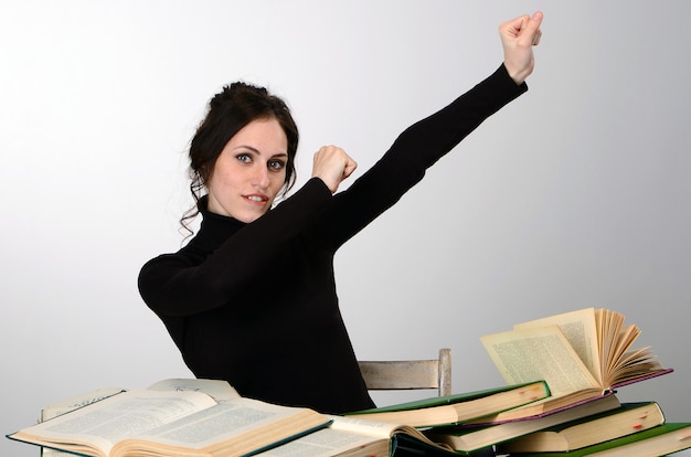 Examen de libros de niña dificultades de suéter negro enseña en la mesa cansado alegra emociones