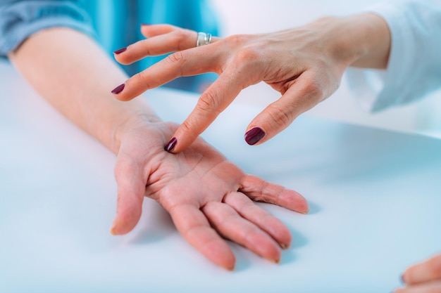 Examen de la mano de un paciente mayor con síndrome del túnel carpiano Imagen de primer plano de la muñeca de una mujer mayor