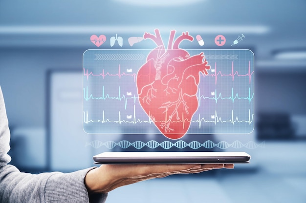 Examen médico en línea y concepto de salud cardíaca de cardiología remota con símbolo de corazón humano rojo y cardiograma en pantalla virtual sobre tableta digital en palma humana