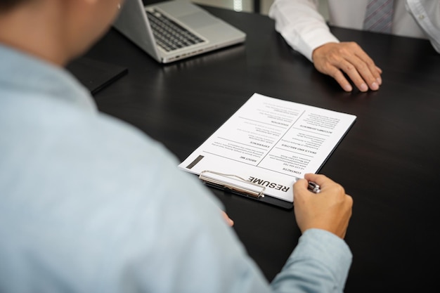 Examinador lendo um currículo durante entrevista de emprego no escritório Conceito de negócios e recursos humanos