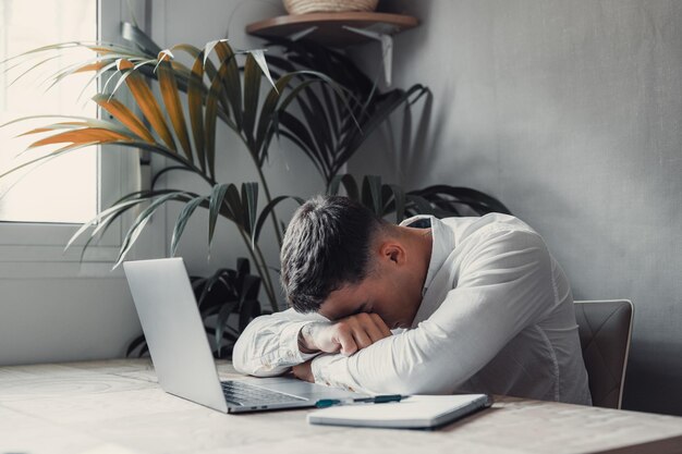 Foto exausto jovem caucasiano empregado de mesa de sono no escritório excesso de trabalho preparando relatório