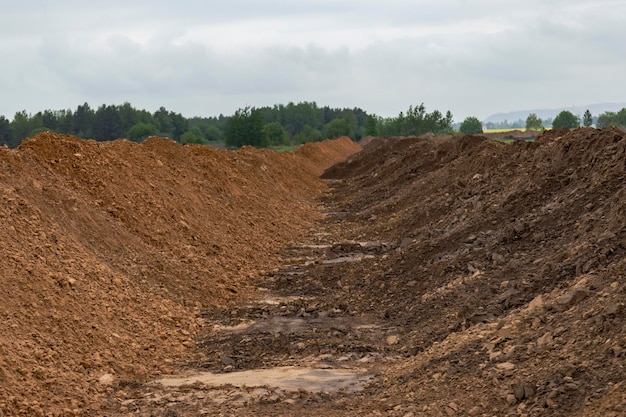 Excavación del suelo en el sitio de construcción Un montón de arena y tierra después del movimiento de tierras Zanja en el suelo