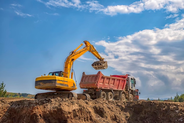 Excavadora amarilla y camión volquete vacío trabajando en el sitio de construcción