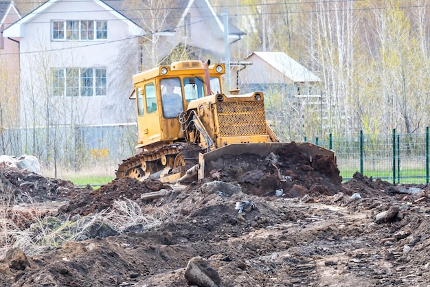 Excavadora amarilla nivelación del suelo en un sitio en construcción