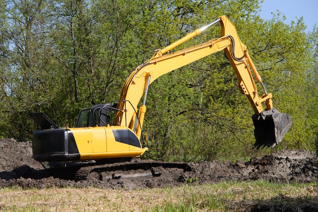 Excavadora antes del día laboral de excavación contra el bosque