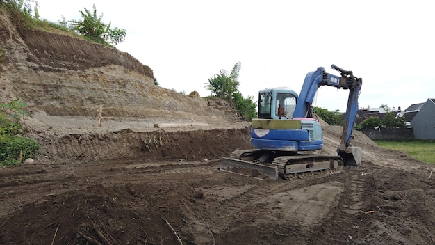 Una excavadora azul está en un camino de tierra.