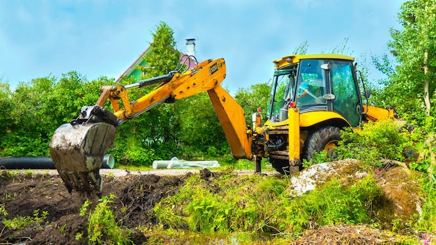 Excavadora con balde en el campo entre una hierba