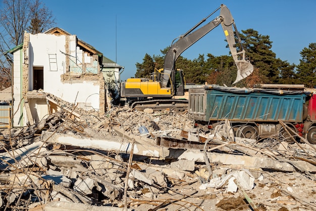 La excavadora carga los restos del edificio destruido en el coche.