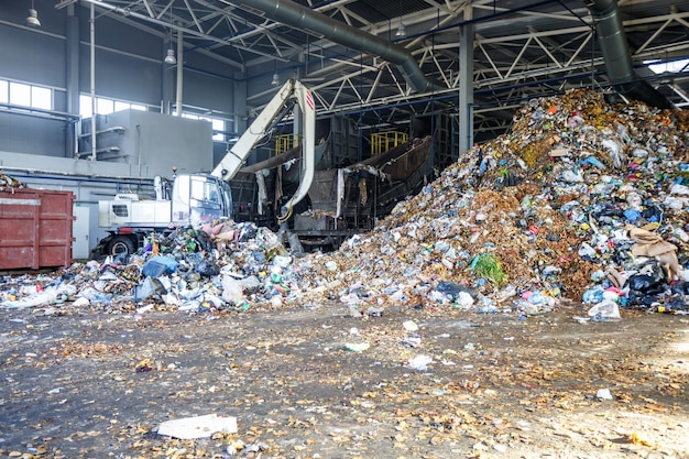 Excavadora en la clasificación primaria de basura en la planta de procesamiento de residuos Recolección separada de basura Reciclaje y almacenamiento de residuos para su posterior eliminación