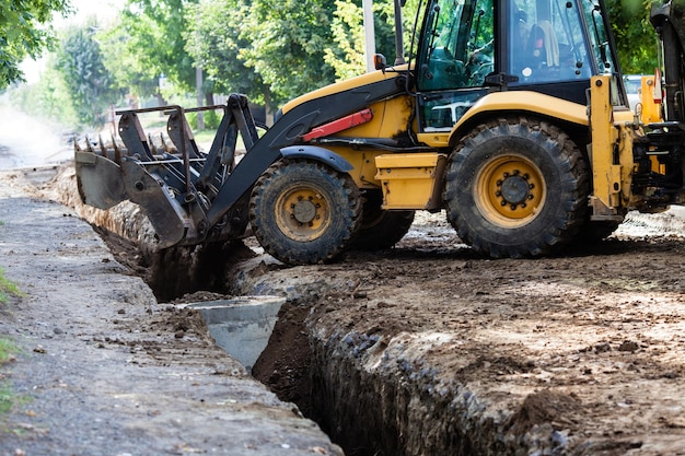 La excavadora se duerme en una trinchera. Construcción en una zona suburbana.