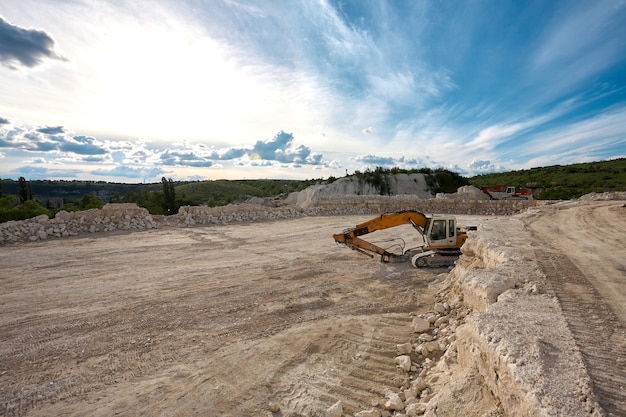 Foto excavadora se encuentra en el fondo de una cantera de piedra.