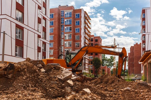 Excavadora excava el suelo en un sitio de construcción en el fondo de edificios de gran altura